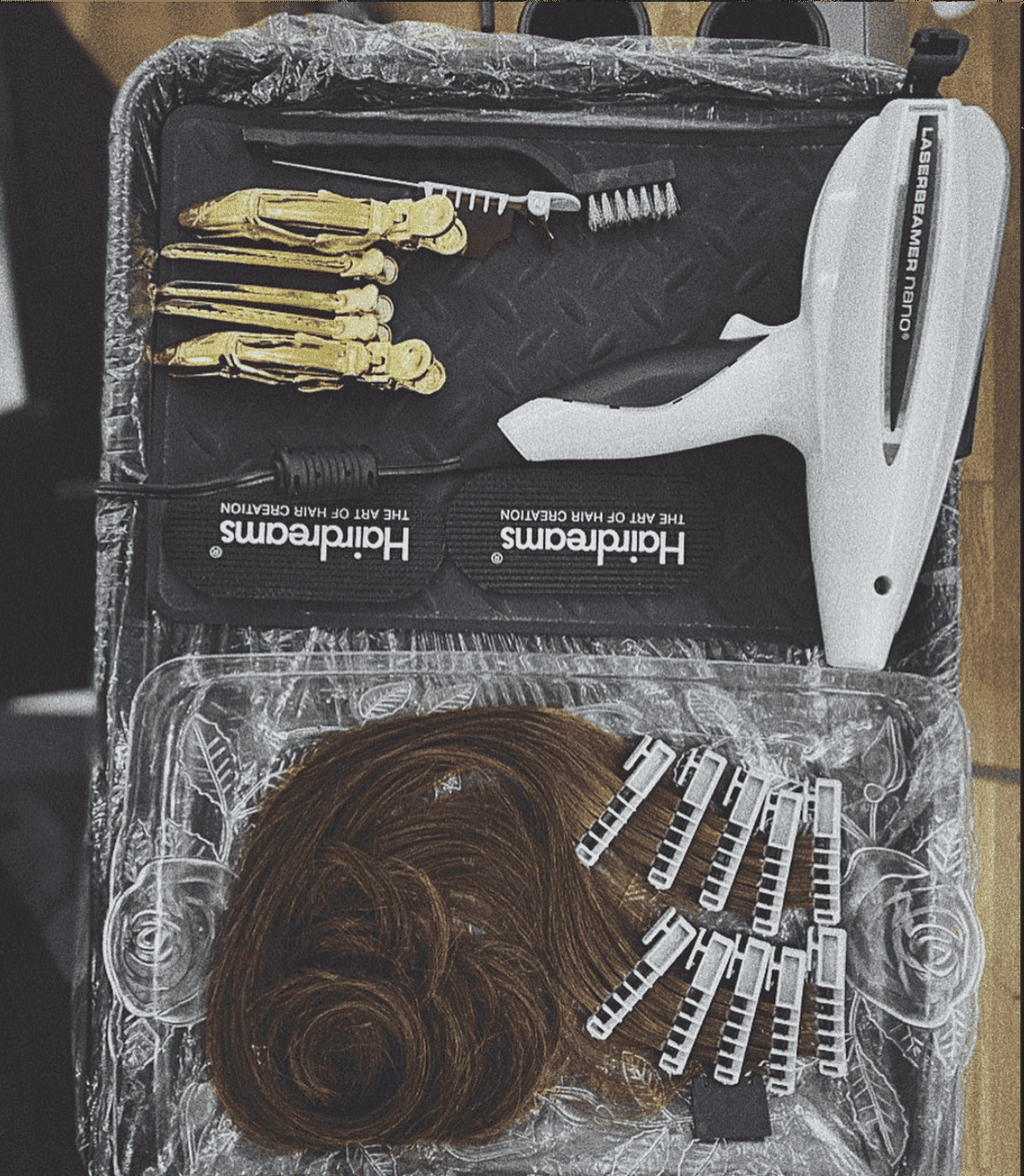 Hair styling tools and accessories, including extensions, clips, and styling device on a tray.