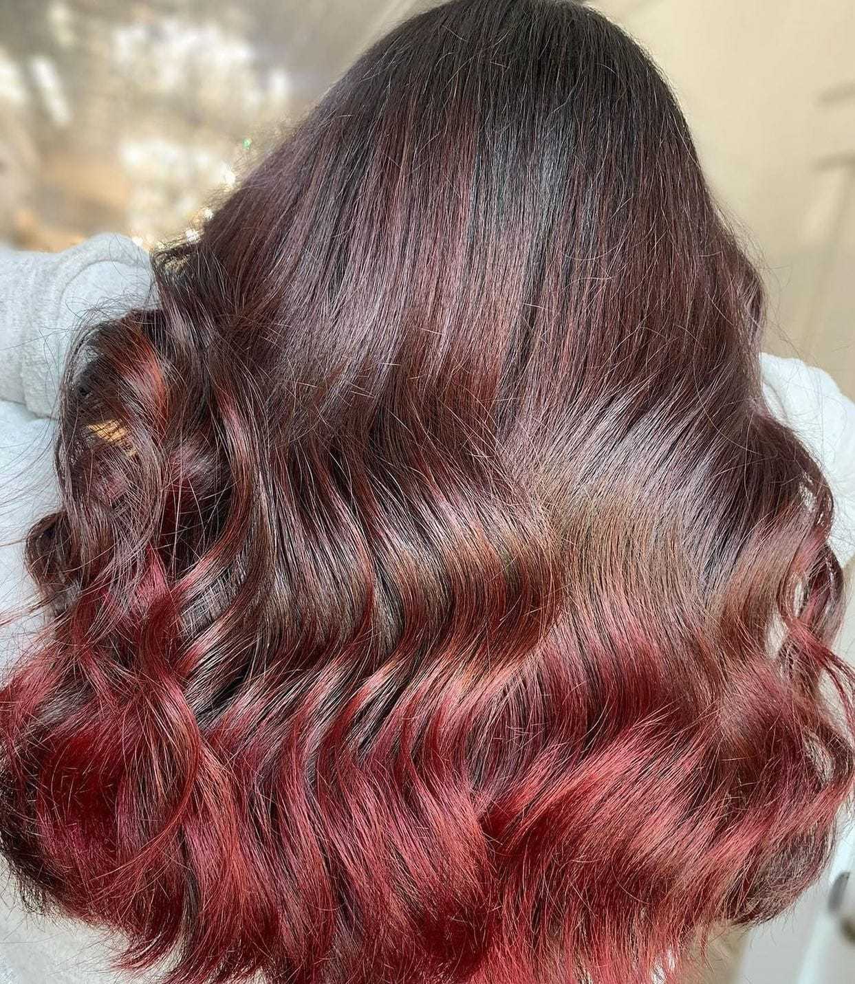 Wavy hair with rich brunette and red ombre highlights.