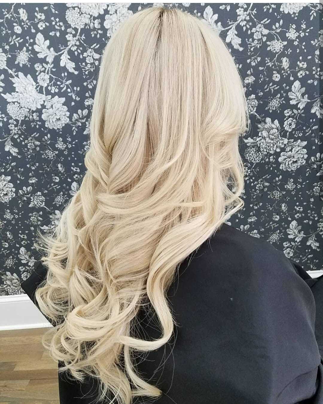 Long, wavy blonde hair against floral wallpaper background.