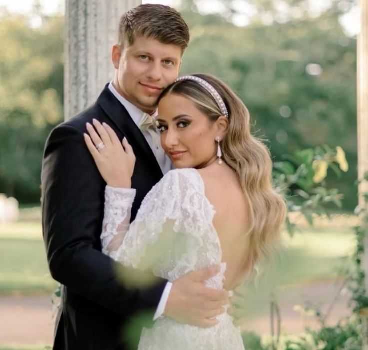 Couple in formal attire embraces outdoors.